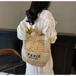 Elegante bolso tote de paja tejida con bordado de París llevado por una modelo real