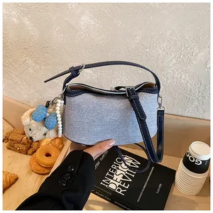 Detail shot of light blue denim bucket bag with teddy charm and blue polka-dot bow accent