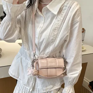 Detail view of a pink woven leather small square crossbody bag worn with white blouse