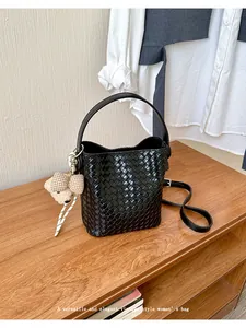 Handmade black woven bucket bag with elegant vintage style and a cute teddy bear charm