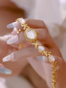 Primer plano de un elegante reloj de pulsera dorado con incrustaciones de nácar.