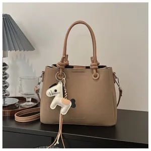 Sophisticated khaki textured handbag featuring a cute horse charm and knotted leather handles
