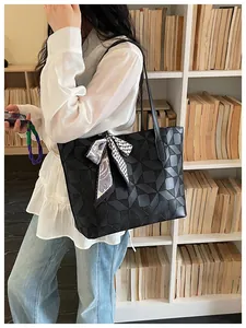 Stylish black geometric patterned large tote bag worn by a model in a library scene.