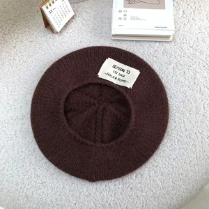 Detailed view of the brown knitted wool beret with a decorative SEASON 13 letter patch.