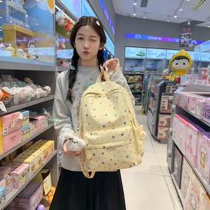 Close-up of a girl holding a yellow star-patterned school backpack in a store setting