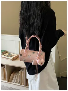 Detailed view of a stylish pink barrel handbag with cute cat patches worn by model