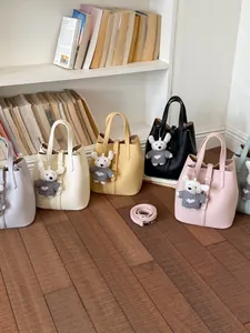 Set of textured bucket bags in pastel colors featuring plush bear charms and crossbody straps