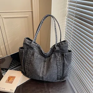 Vue détaillée d'un sac cabas en denim délavé gris avec des poches latérales spacieuses.