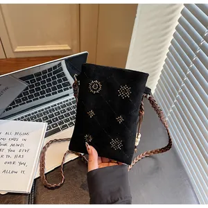 Close-up detail of black velvet crossbody phone bag with gold bead accents and strap.
