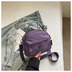 Detalle del bolso bandolera de nailon morado con asa superior y correa ajustable