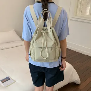 Vista posterior de una mochila beige minimalista con cordón llevada por una persona.