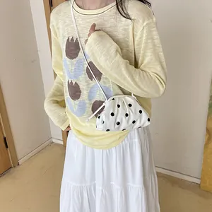 Small white polka dot pleated dumpling bag worn crossbody with summer casual outfit