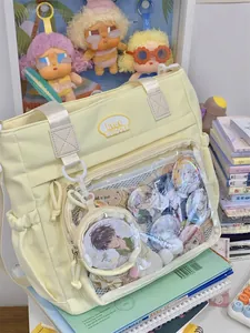 Cream-colored ita bag with clear window filled with decorative anime character badges.