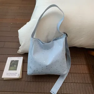 Close-up of light blue canvas tote bag featuring silver sequin star patterns.