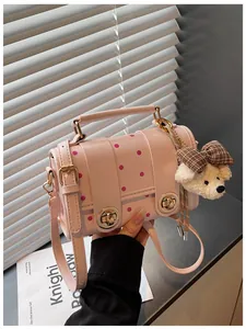 Detail view of pink retro polka dot crossbody bag featuring a cute white bear charm