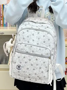 Close-up detail of gray canvas backpack featuring white star patterns and tassels
