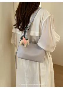 Detail view of a minimalist faux leather shoulder underarm bag with a cute winged pony charm.