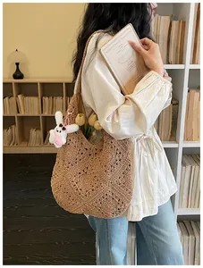Dettaglio di borsa tote in paglia intrecciata marrone con ciondolo a forma di coniglio