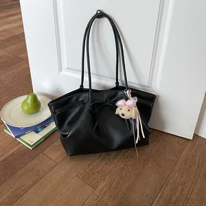 Elegante zwarte grote draagtas met strik en pluche hondenbedeltje op een houten vloer