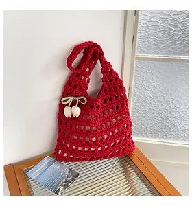 Vista detallada de un bolso de ganchillo rojo grande con un colgante de tulipán blanco