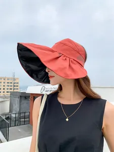 Side view of woman wearing a stylish large orange sun visor hat with black vinyl lining outdoor.