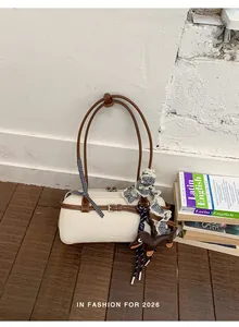 Detailed view of cream and brown colorblock Boston bag with gingham ribbon and puppy charm