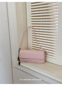 Detailed view of a trendy pink underarm baguette bag against a white window background