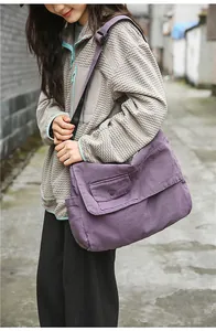 Detailed shot of a model wearing a large capacity purple canvas messenger bag outdoors