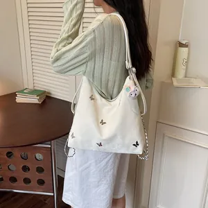 Lifestyle shot of a woman carrying a white large capacity bag with butterfly embroidery