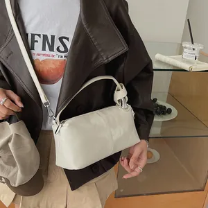 Detailed view of a vintage off-white pillow bag worn with a brown jacket