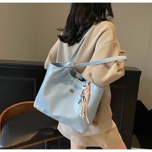 A lifestyle shot showing a model with a glossy light blue tote bag on her shoulder.