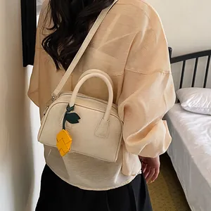 Detailed view of an elegant cream pillow bag with a unique yellow fruit charm