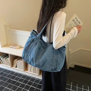 Sac fourre-tout en jean bleu avec poches latérales, porté par un mannequin dans un café.