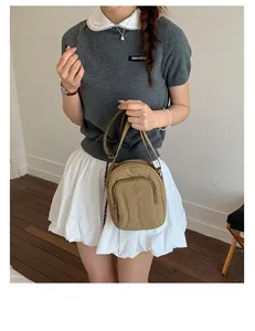 Frau trägt eine stilvolle khakifarbene Mini-Umhängetasche aus Nylon zum weißen Rock