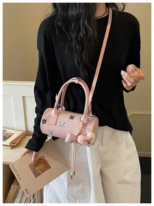 Stylish pink barrel shoulder bag with cute animal prints and plush heart charm on model