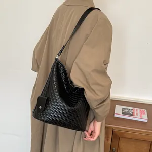 Gedetailleerde weergave van een zwarte geweven emmerzak met een beige trenchcoat