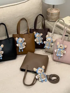 Fashionable lychee pattern bucket bags in multiple colors with cute plush bear charms.