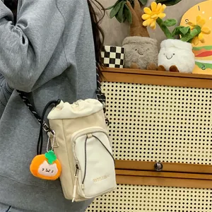 Detailansicht der cremefarbenen Beuteltasche mit einem niedlichen orangefarbenen Katzenanhänger