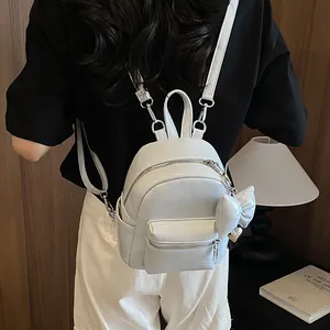Nahaufnahme eines weißen, glänzenden Mini-Rucksacks aus PU-Leder mit Schleifenanhänger.