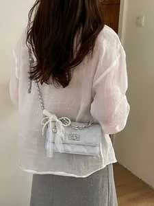Fashionable quilted light blue crossbody bag featuring elegant lace and a pearl bow