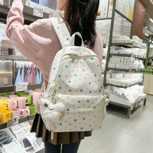 Cute Japanese style white backpack with colorful star patterns shown in a lifestyle setting.