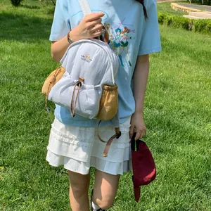 Primer plano de una elegante mini mochila gris claro con bolsillos laterales marrones al aire libre