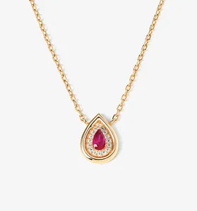 Close-up view of elegant gold teardrop necklace featuring a pear-cut red ruby and diamond halo.