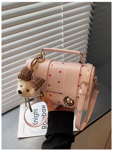 Close-up detail of a pink polka dot retro crossbody bag featuring a cute bear plush charm