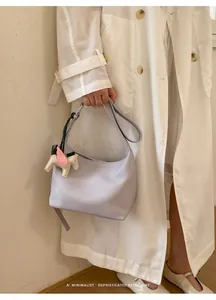 Close-up detail of a minimalist lavender leather shoulder bag with a horse charm