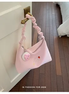 Detalle de un bolso hobo rosa con asa rizada y bordado de fresas para uso diario.