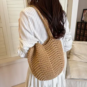 Handcrafted woven shoulder bag in khaki, shown as a stylish accessory for a spring outfit.