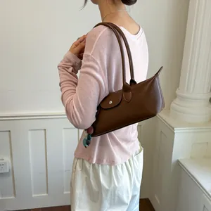 Vue latérale d'un sac sous le bras en cuir marron porté par un mannequin dans un décor épuré
