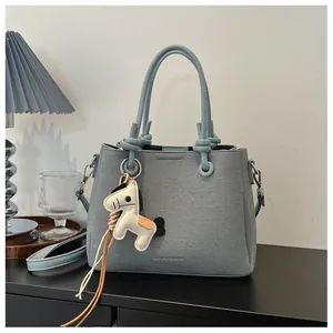 Light blue textured bucket bag with cute horse pendant on a minimalist desk setup