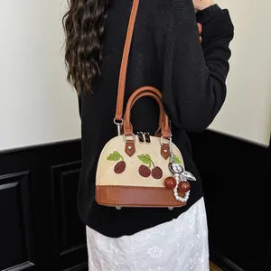 Vista detallada de un bolso bandolera de moda con bordado de cerezas usado por una modelo